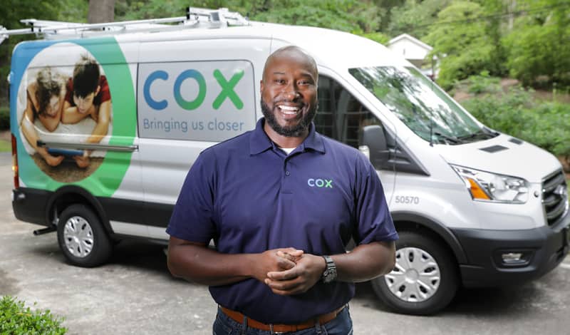 man smiling in front of Cox Van