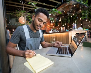 Guy taking notes from laptop