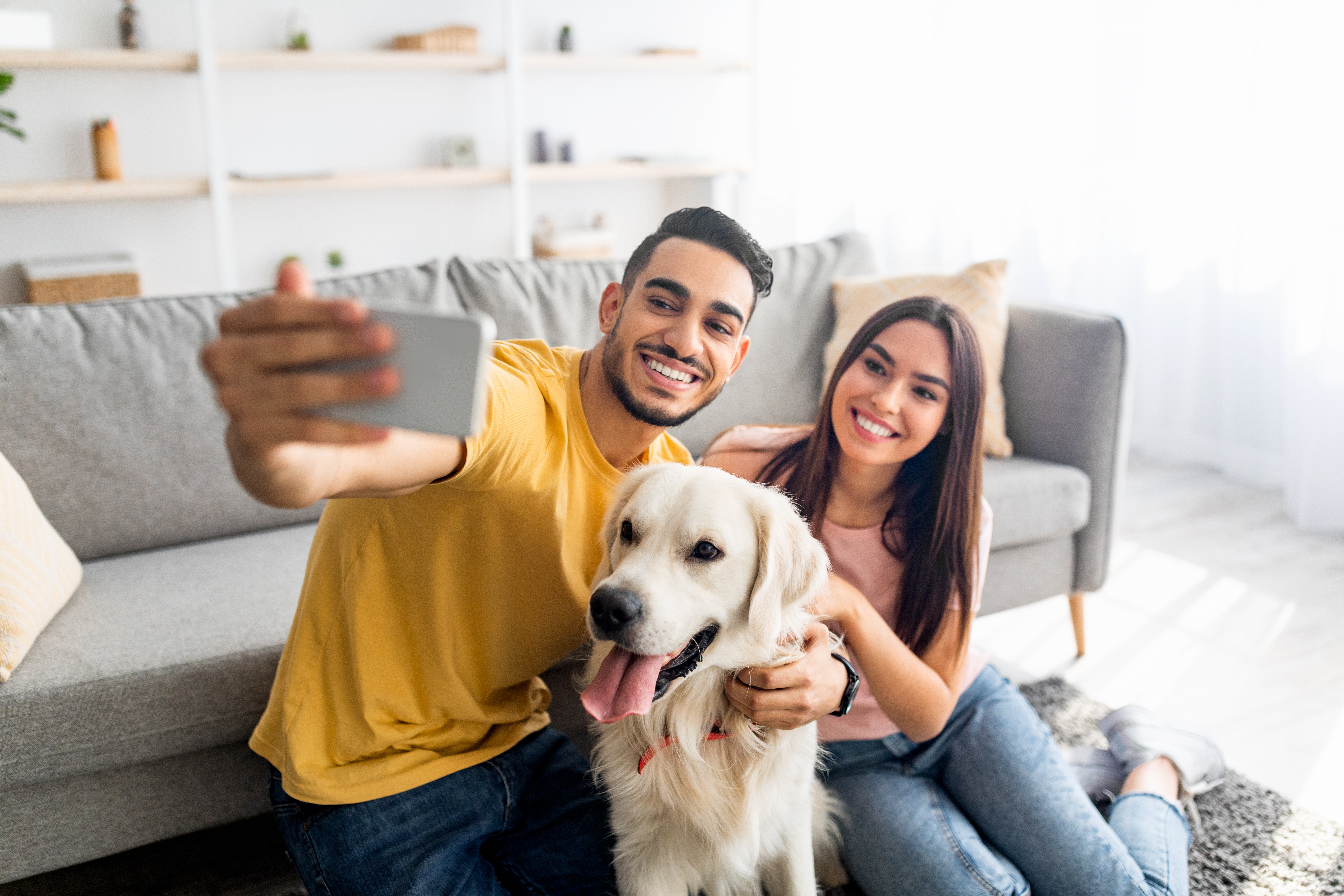 Young couple with pet dog taking a selfie in home