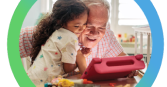 Abuelo y nieta sonríen sentados frente a una tablet
