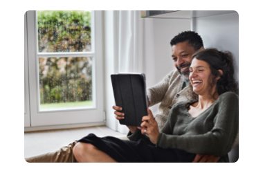 Couple sitting by window looking at tablet