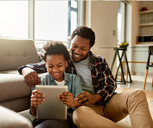 Father and son sitting on floor looking at ipad