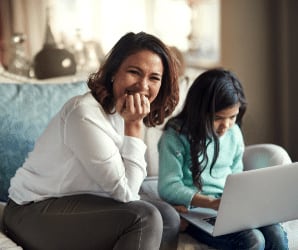Mom smiling while daughter is on laptop