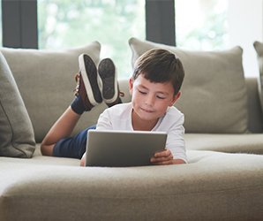 Young boy looking at tablet on couch