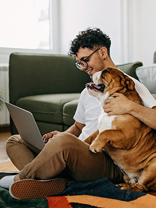 man-with-dog-sitting-on-floor-using-laptop