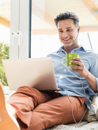 Hombre bebiendo café con una laptop en su regazo