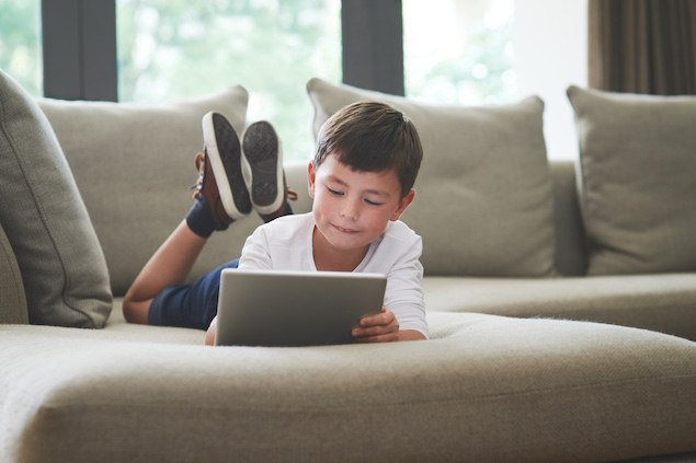 Young boy looking at tablet on his couch